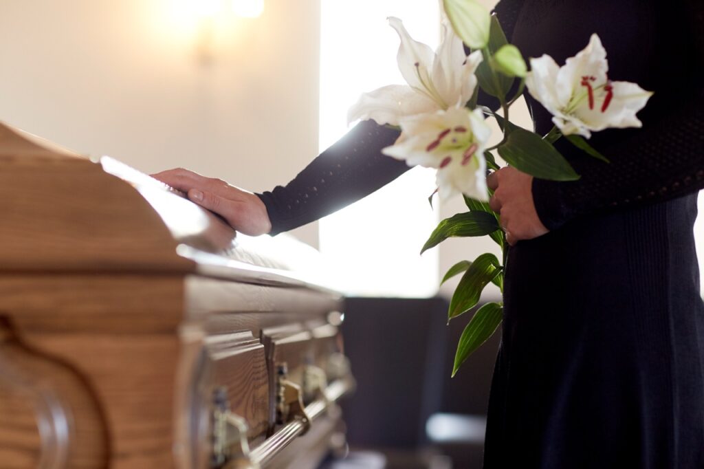 Woman laying flowers on a casket at a funeral service
