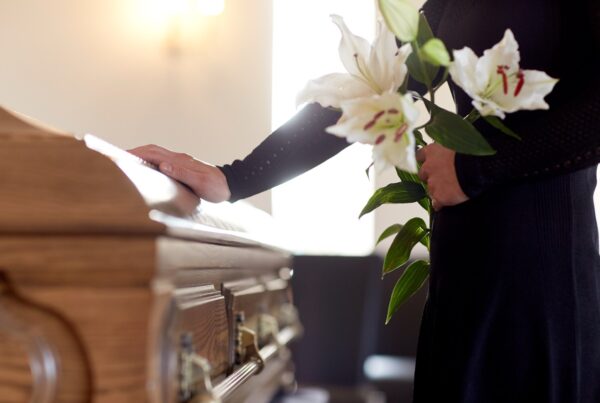 Woman laying flowers on a casket at a funeral service