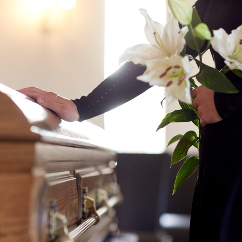 Woman laying flowers on a casket at a funeral service